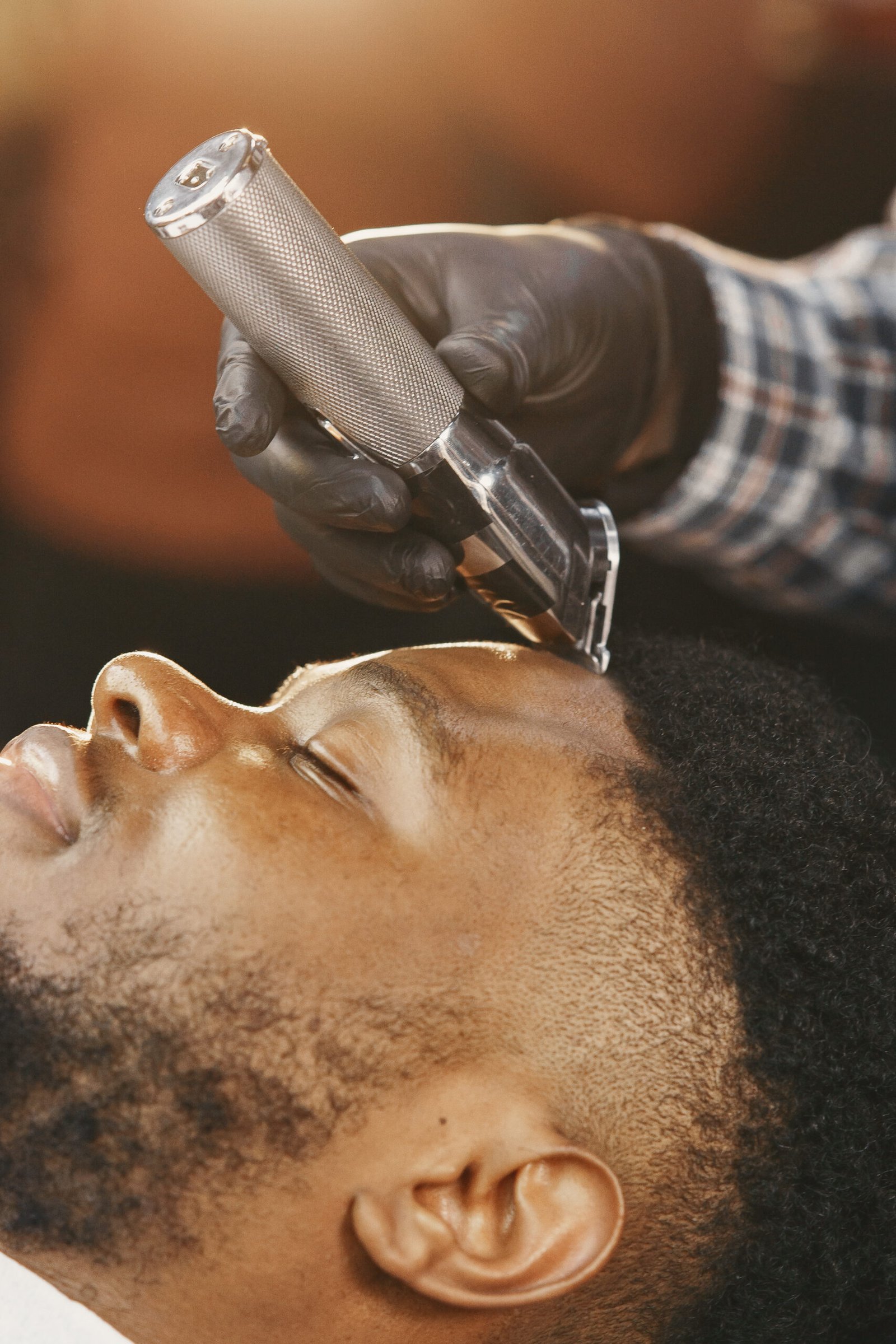 African American man receives a precise haircut with a hair clipper. Close-up view.